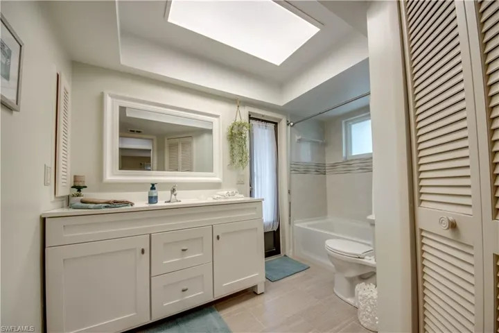 Full bathroom with tile floors, toilet, vanity, and tiled shower / bath