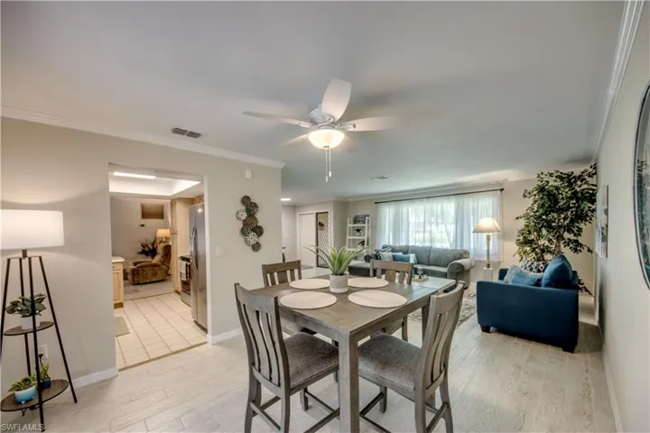 Dining room with ceiling fan, crown molding, and light tile flooring