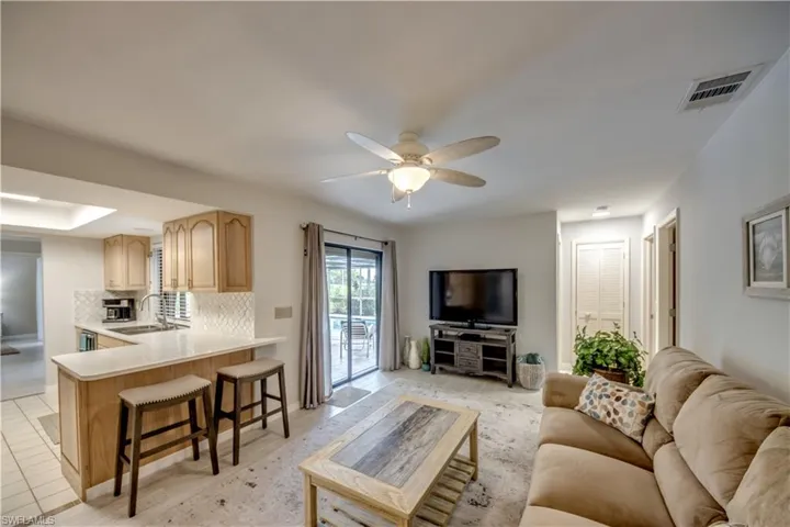 Living room with ceiling fan, light tile flooring, and sink