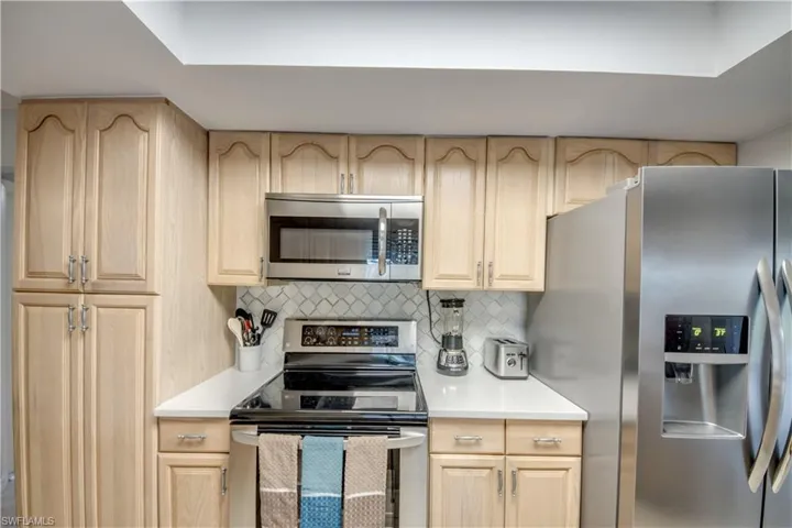 Kitchen with light brown cabinets, tasteful backsplash, and appliances with stainless steel finishes