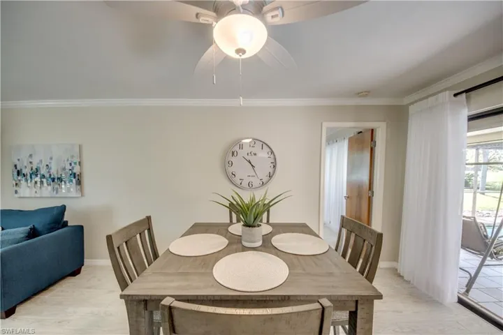 Dining room with ornamental molding, ceiling fan, and light wood-type flooring