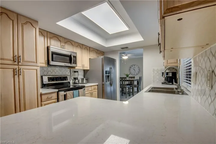 Kitchen with stainless steel appliances, ceiling fan, tasteful backsplash, a tray ceiling, and sink