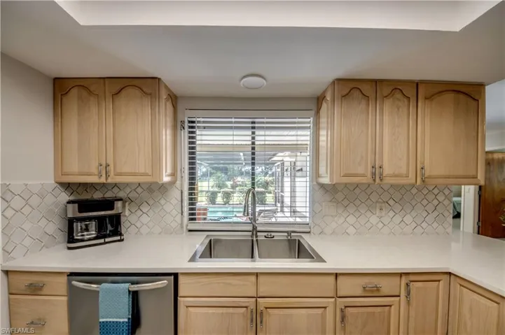 Kitchen with dishwasher, sink, light brown cabinetry, and backsplash