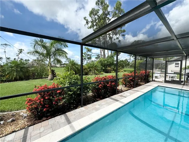 View of swimming pool featuring a lanai and a lawn