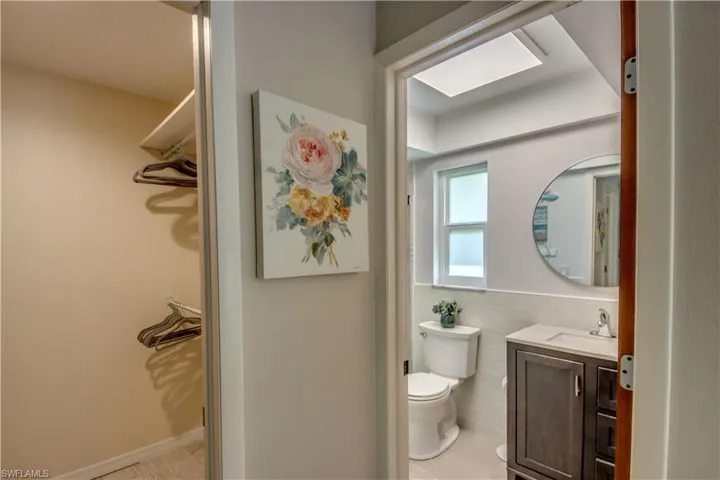 Bathroom with tile flooring, vanity, toilet, and tile walls