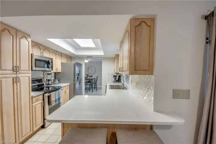 Kitchen featuring backsplash, appliances with stainless steel finishes, sink, and kitchen peninsula