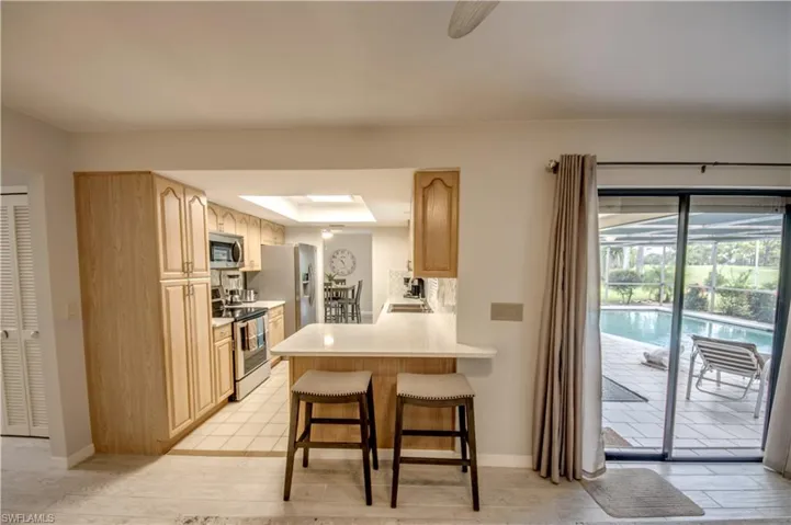 Kitchen with light brown cabinets, a kitchen breakfast bar, light hardwood / wood-style floors, kitchen peninsula, and stainless steel appliances