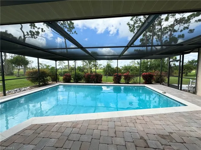 View of pool with a patio area and glass enclosure