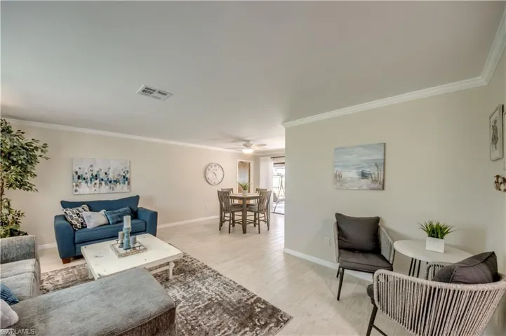 Living room with ceiling fan, light hardwood / wood-style floors, and crown molding