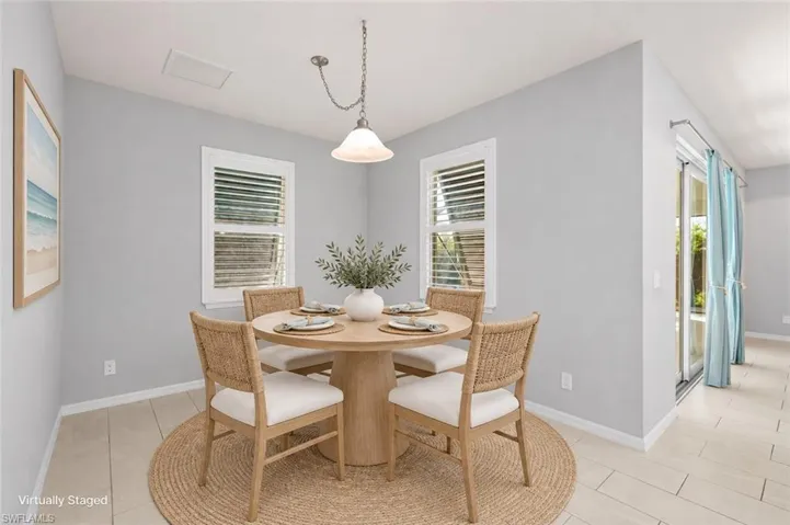 VIRTUALLY STAGED Light-filled room featuring neutral-toned tile flooring, dual windows with plantation shutters, and a central pendant light fixture with a glass shade