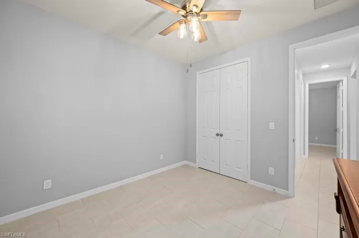 Room featuring light-toned tile flooring, neutral wall paint, and a ceiling fan with integrated lighting