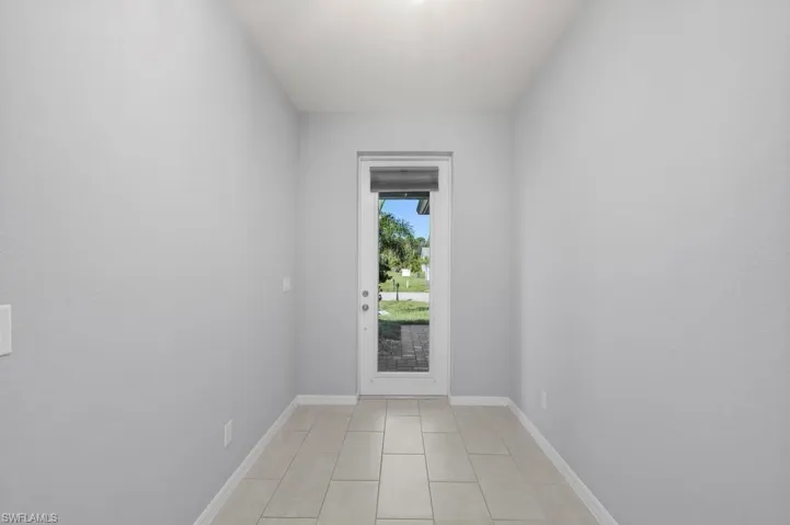 Entryway featuring neutral-toned wall paint, ceramic tile flooring, and a glass-paneled exterior door