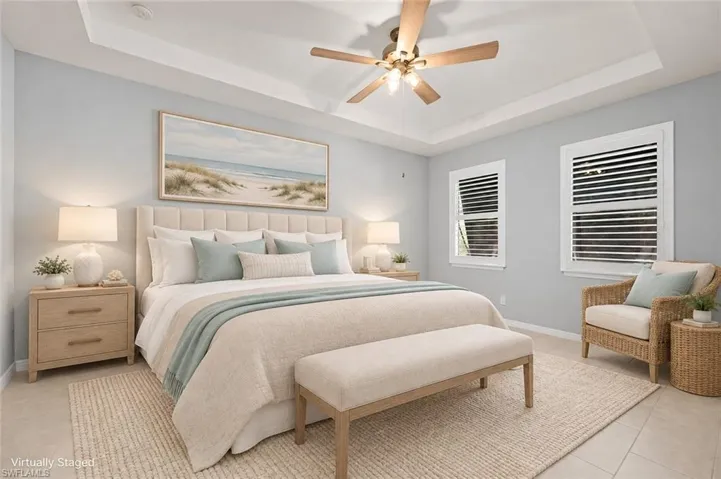 VIRTUALLY STAGED Tray ceiling featuring a central multi-blade ceiling fan with integrated lighting and two windows with plantation shutters