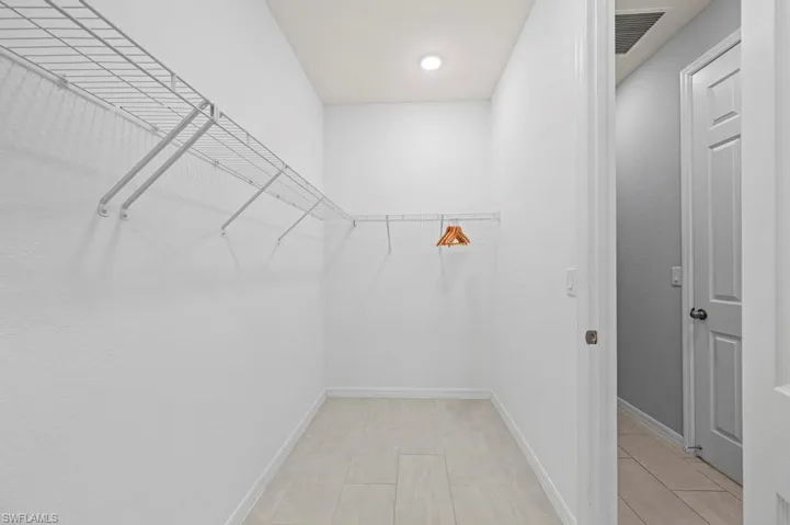 Walk-in storage space featuring neutral wall paint, tile flooring, and white wire shelving
