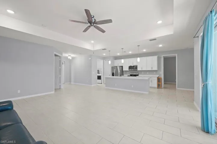 Tray ceiling with recessed lighting, tile flooring, kitchen island with breakfast bar, built-in cabinetry, and multi-pendant lighting