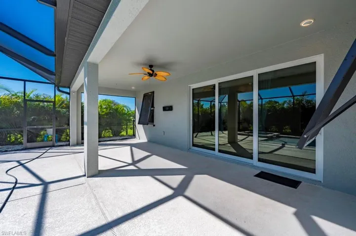Covered lanai featuring a concrete floor, screened enclosure, ceiling fan, and sliding glass doors