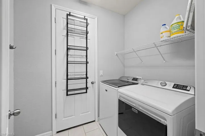 Laundry area featuring tile flooring, white interior door, and wall-mounted wire shelving