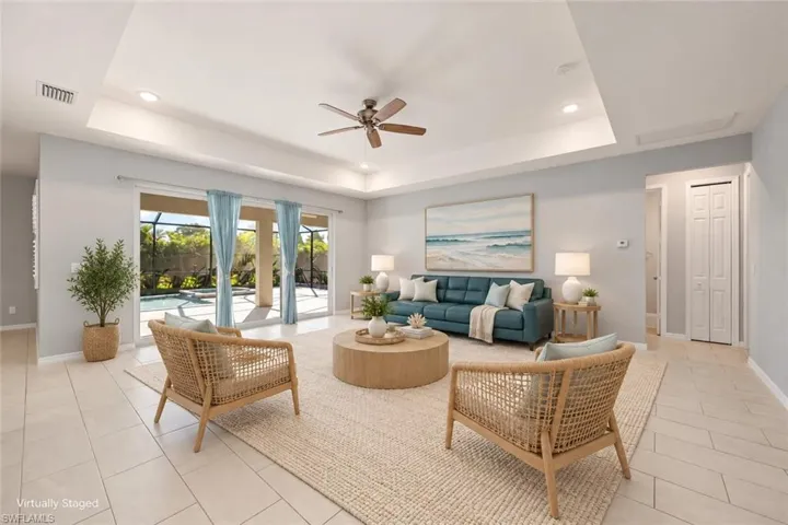 VIRTUALLY STAGED Spacious room featuring a tray ceiling, recessed lighting, tile flooring, and large sliding glass doors providing outdoor access