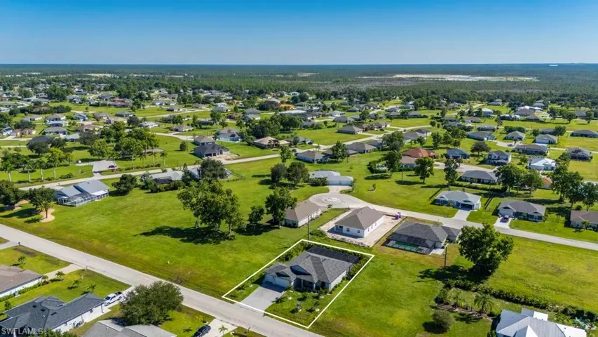 Single-story residence featuring a multi-gable roofline, attached two-car garage, concrete driveway, and expansive grass lot
