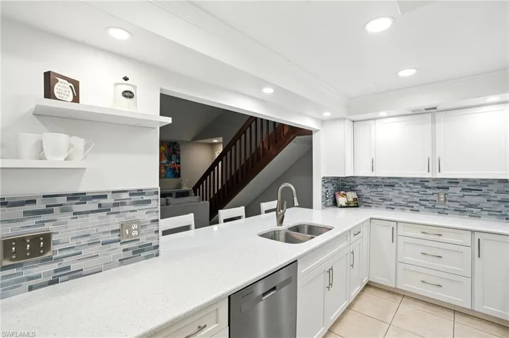 Kitchen featuring stainless steel dishwasher, open shelves, recessed lighting, light tile patterned floors, and backsplash