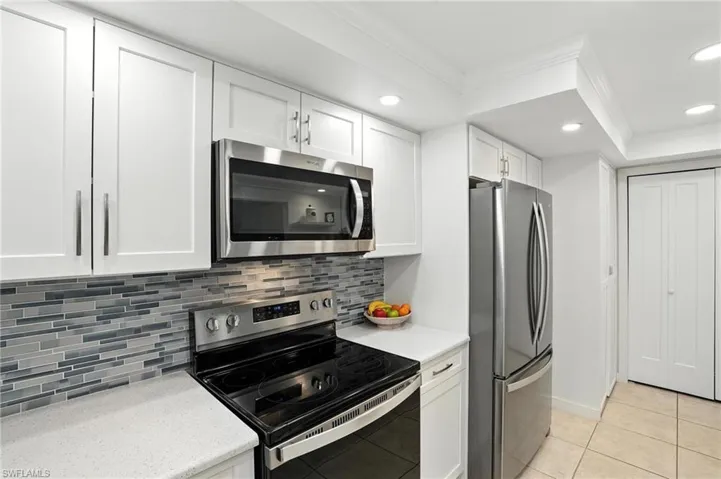 Kitchen with stainless steel appliances, ornamental molding, tasteful backsplash, white cabinetry, and recessed lighting