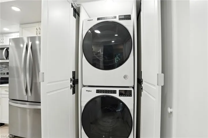 Laundry room with stacked washer / dryer, recessed lighting, and a barn door