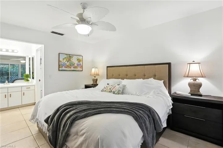 Bedroom featuring light tile patterned flooring, ensuite bathroom, and ceiling fan