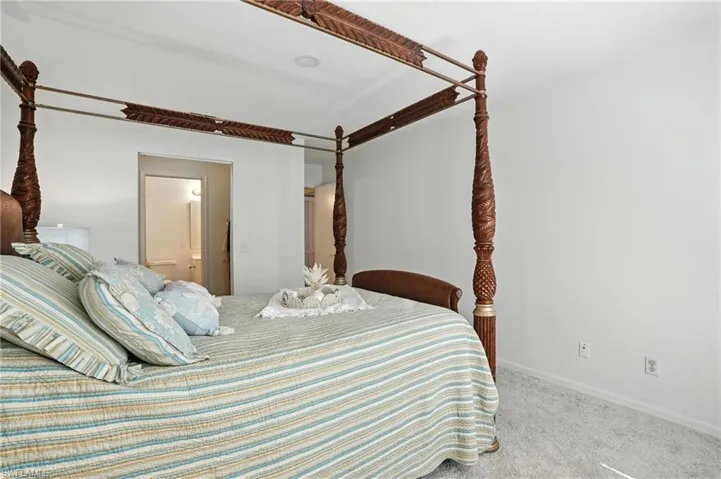 Carpeted bedroom featuring connected bathroom and baseboards