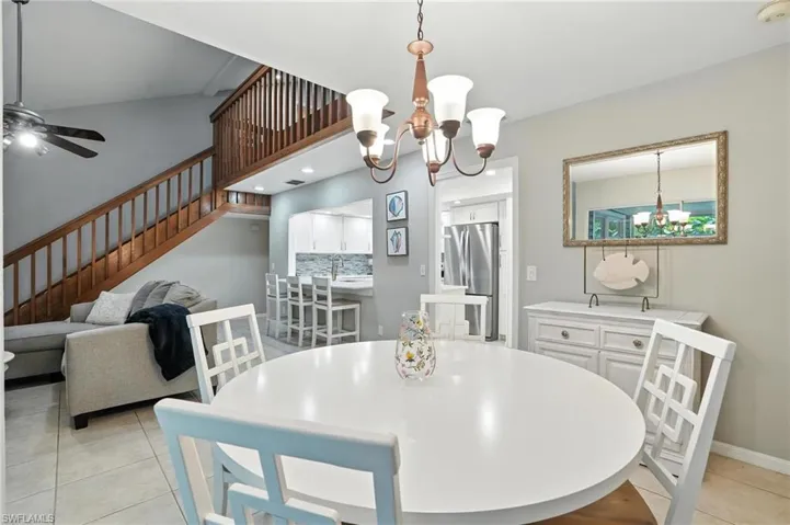 Dining room with a chandelier, stairs, light tile patterned flooring, and a ceiling fan