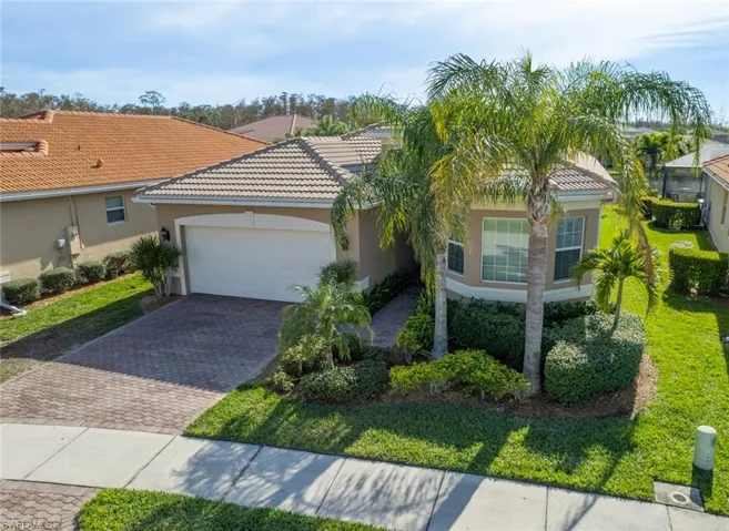 Mediterranean / spanish home with a garage, decorative driveway, stucco siding, a front lawn, and a tiled roof
