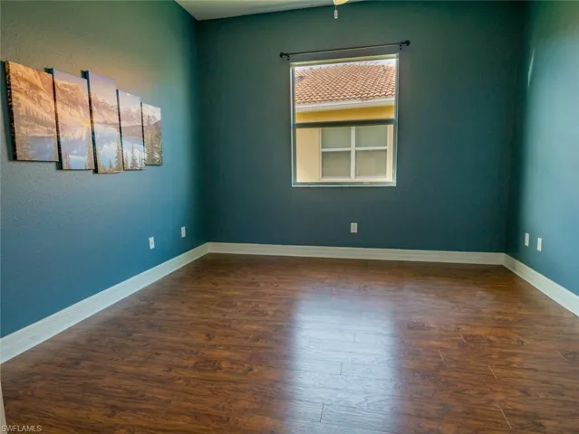 Empty room featuring dark wood-style floors and a textured wall