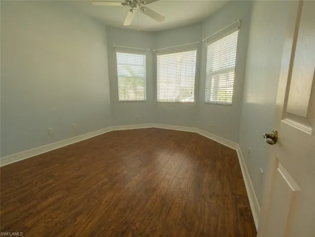 Empty room with dark wood-style floors and a ceiling fan