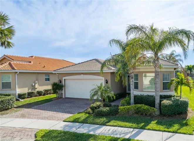 View of front of home with a garage, stucco siding, decorative driveway, and a front lawn