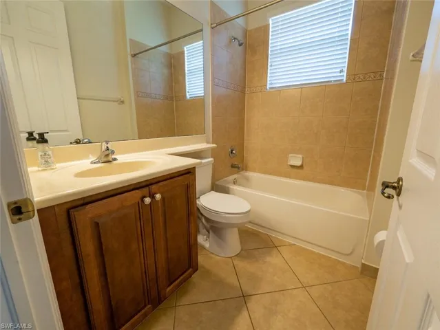 Full bath with vanity, washtub / shower combination, and light tile patterned flooring