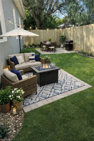Fenced backyard featuring a patio, grilling area, outdoor dining area, and a fire pit
