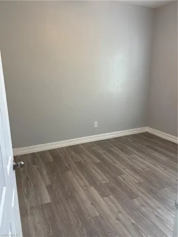 Spare room featuring baseboards and dark wood finished floors