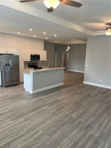 Kitchen with ceiling fan, fridge, white cabinetry, dark wood-style flooring, and recessed lighting