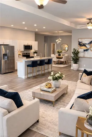 Living area with light wood-style floors, a ceiling fan, and recessed lighting