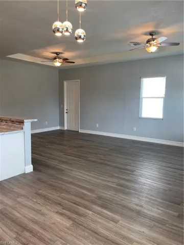 Unfurnished room with ceiling fan, dark wood-type flooring, and a chandelier
