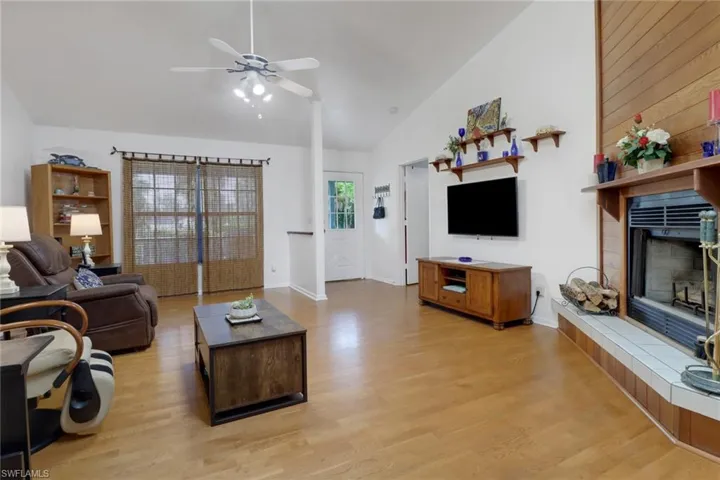 Living room featuring a fireplace, wooden walls, ceiling fan, and hardwood / wood-style flooring