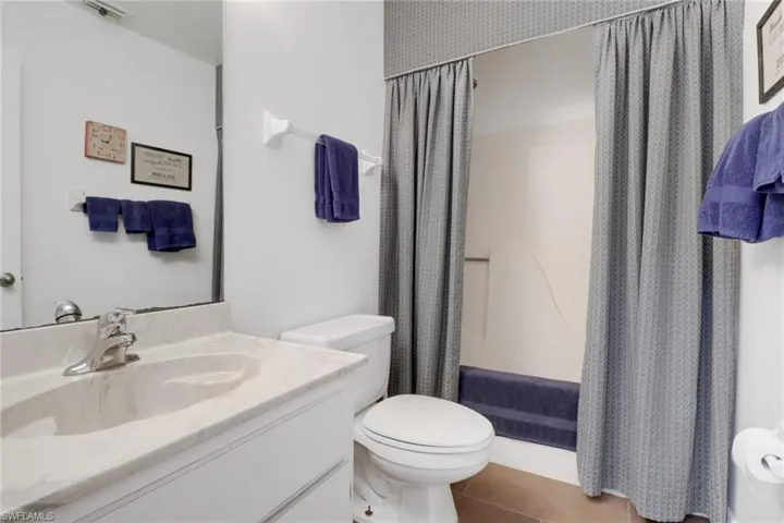 Bathroom with tile patterned flooring, toilet, walk in shower, and vanity