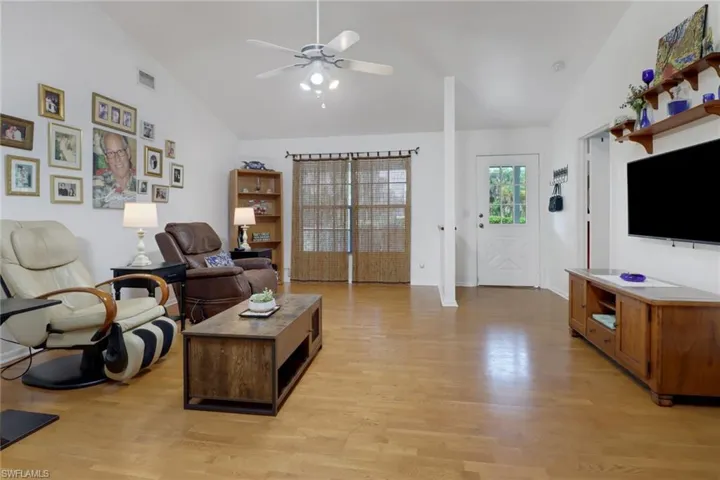Living room featuring ceiling fan, light wood-type flooring, and lofted ceiling