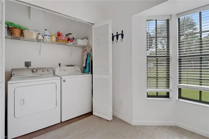 Laundry area with light tile patterned flooring, washing machine and clothes dryer, and plenty of natural light
