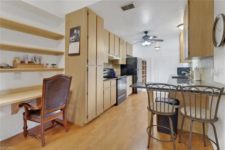 Kitchen featuring tasteful backsplash, sink, black appliances, light wood-type flooring, and ceiling fan