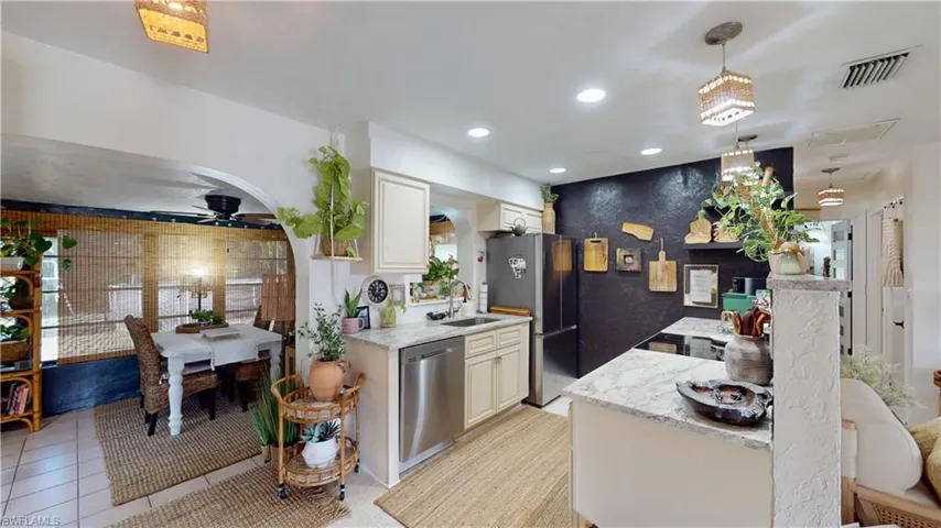 Kitchen with light tile patterned flooring, pendant lighting, ceiling fan, stainless steel appliances, and light stone countertops
