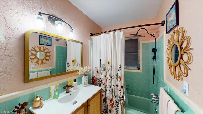 Bathroom featuring shower / tub combo with curtain, vanity, and backsplash