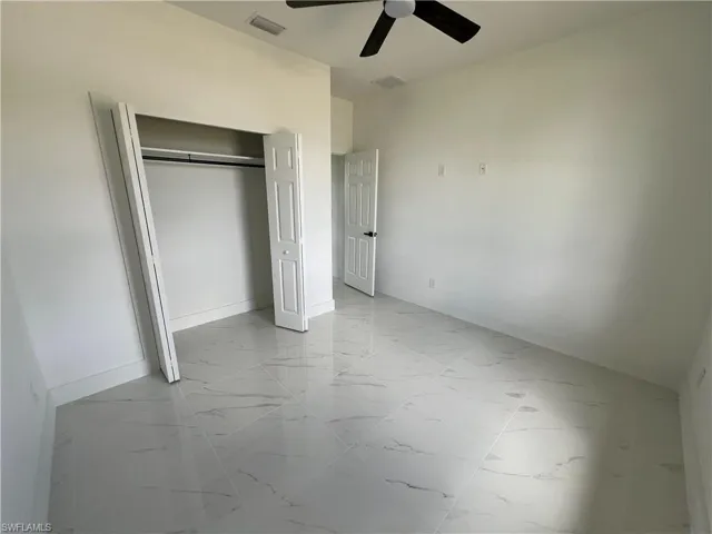 Unfurnished bedroom featuring light tile patterned flooring, ceiling fan, and a closet