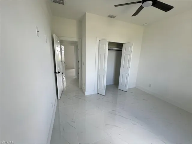 Unfurnished bedroom featuring ceiling fan, a closet, and light tile patterned floors