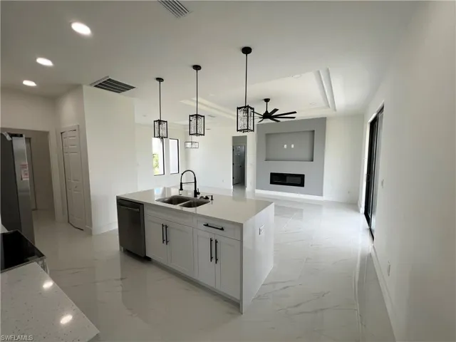 Kitchen with sink, light tile patterned floors, black dishwasher, and ceiling fan