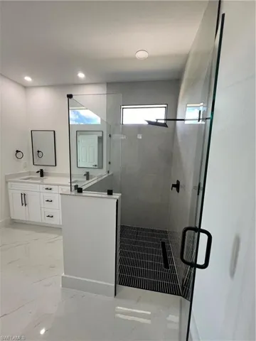 Bathroom featuring tile patterned flooring, vanity, and walk in shower